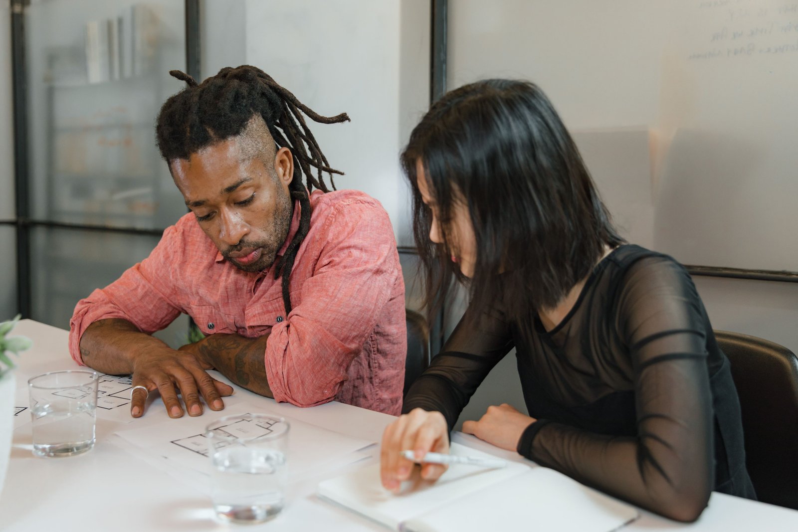 Two colleagues collaborate on design plans in a modern office setting. Focus on teamwork.