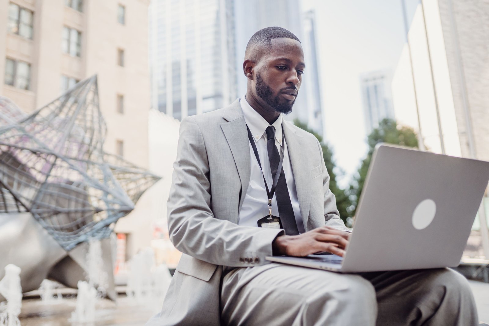 Business professional using a laptop in urban outdoor setting. Focused on remote work tasks.