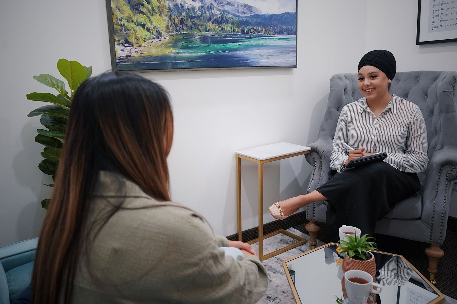 Two women in a cozy office setting engage in a friendly and casual meeting.