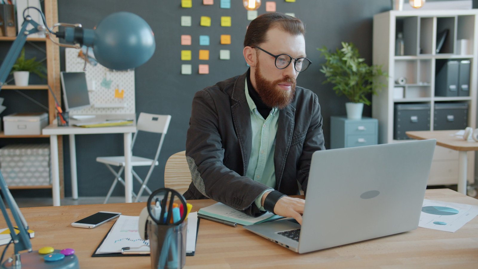 Businessman analyzing data on laptop in modern office setting.