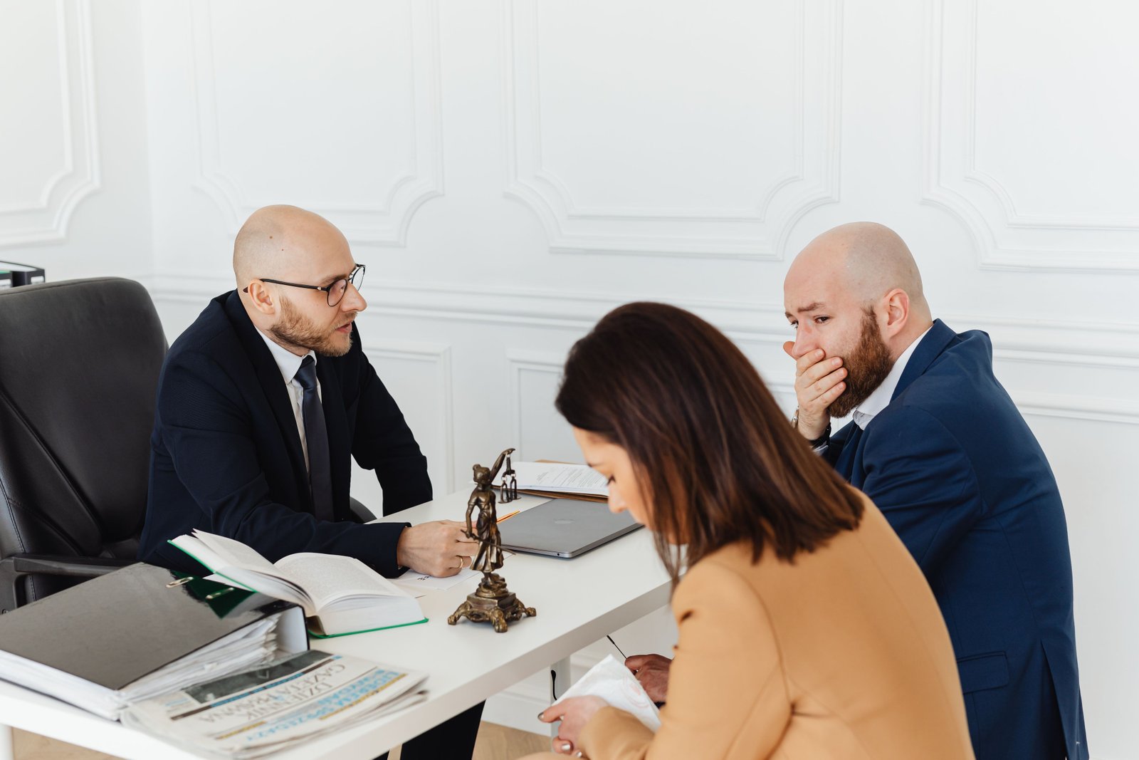A serious legal consultation in a professional office environment involving three adults.