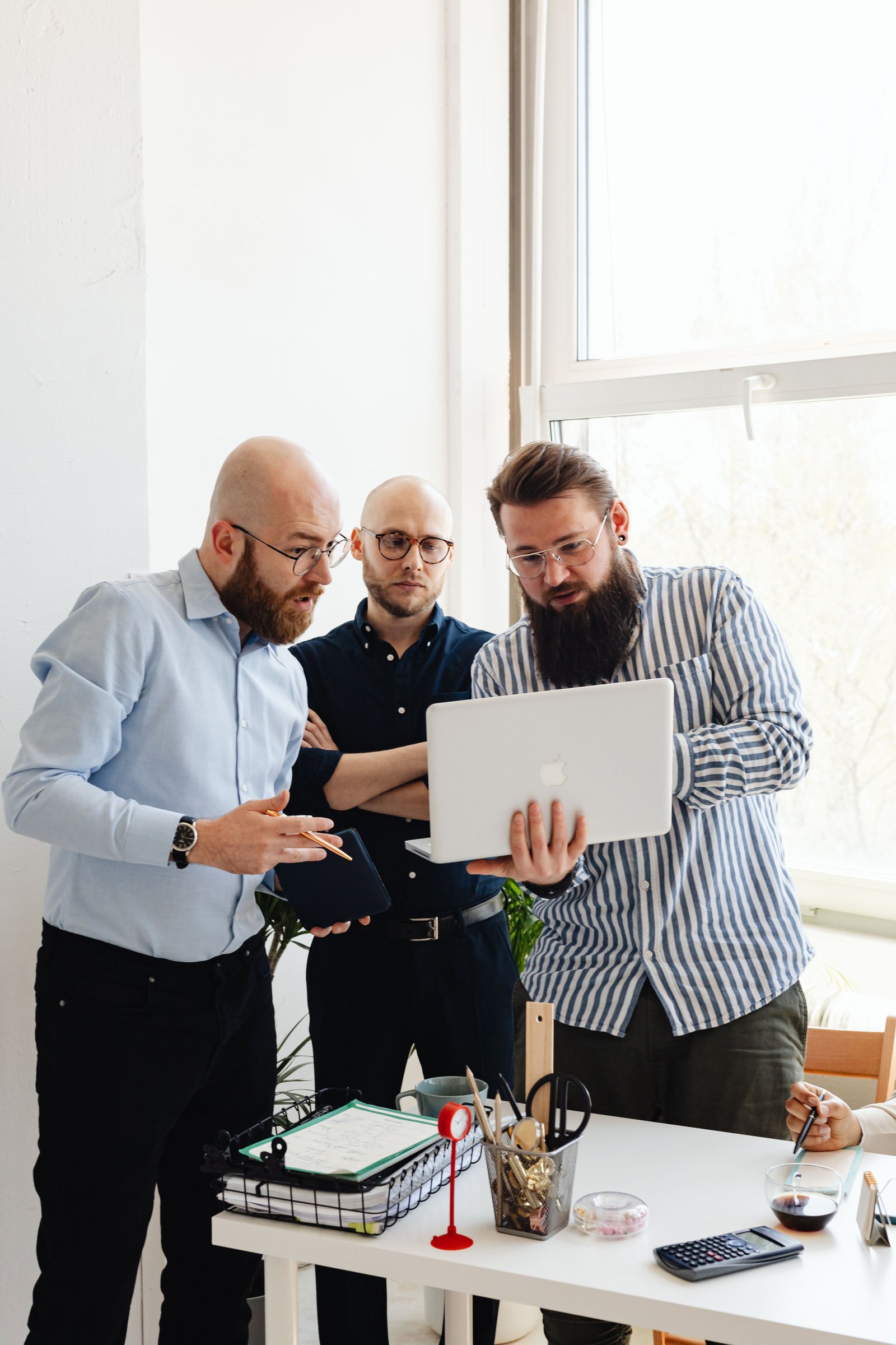 A group of business professionals discussing work on a laptop in an office setting.