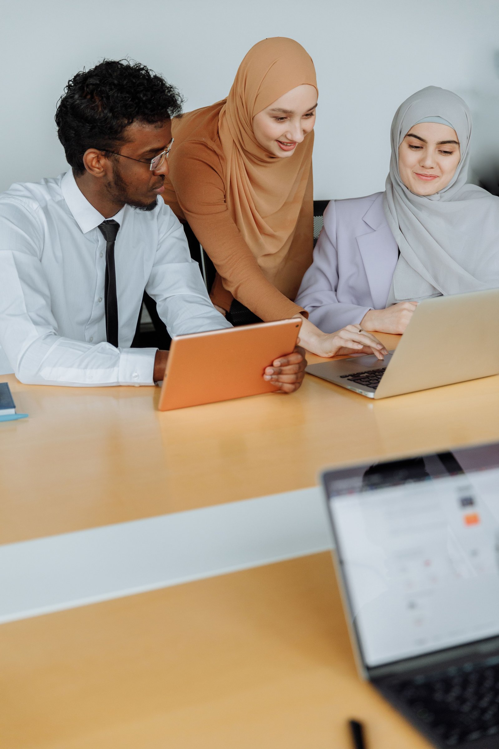 Diverse team working together using laptops and tablets in a modern office setting.