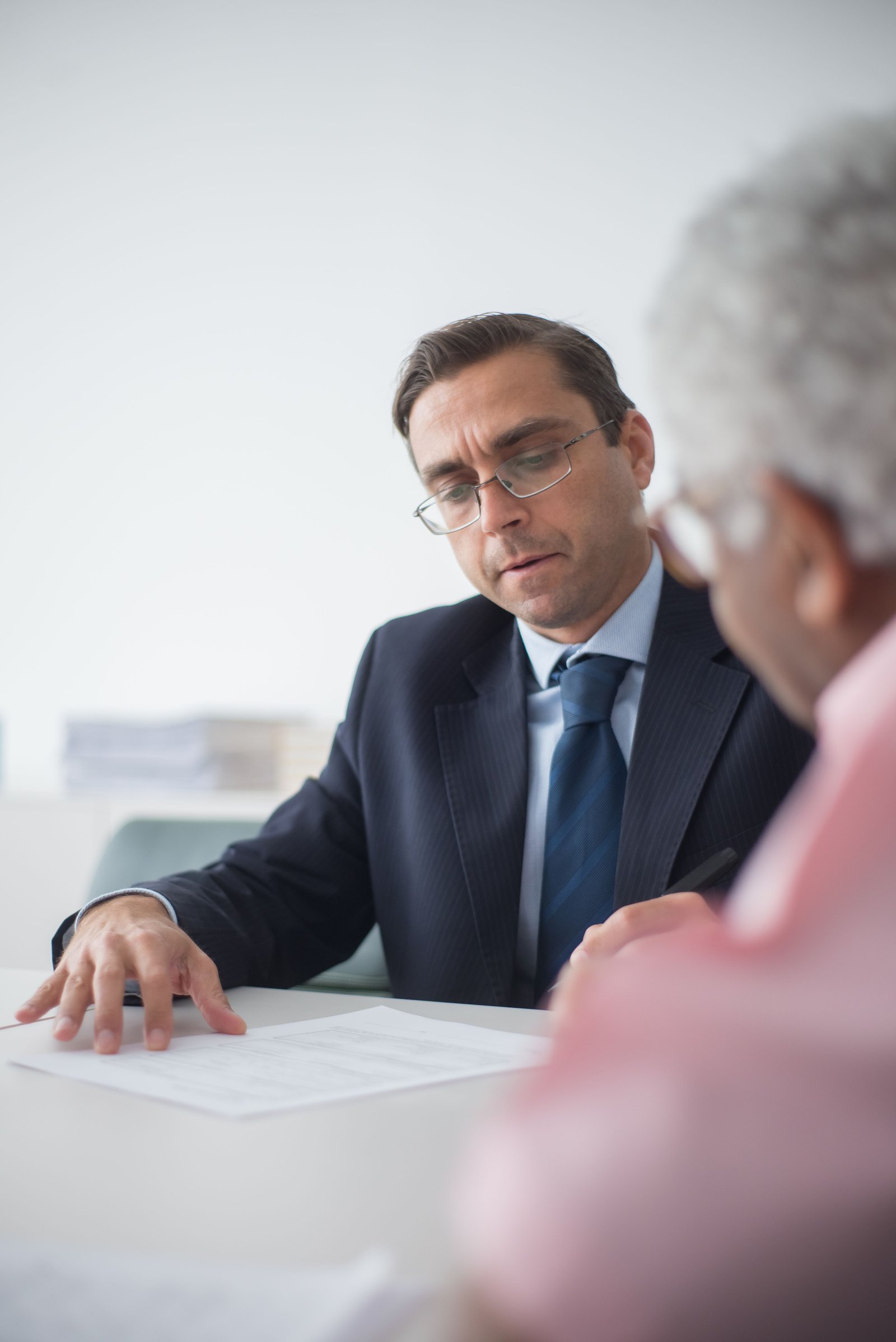 Senior man in discussion with consultant in office setting, reviewing documents.