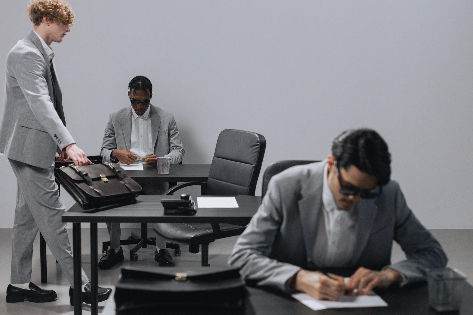 Business office with diverse employees in gray suits working at desks in an indoor setting.